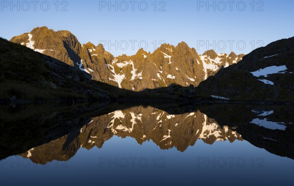Rocky mountain peaks reflected in a small pond, mountain landscape with alpenglow at sunrise, at the Trollfjord Hytta, at the Trollfjord, Lofoten and Vesterålen, Nordland, Norway, Europe
