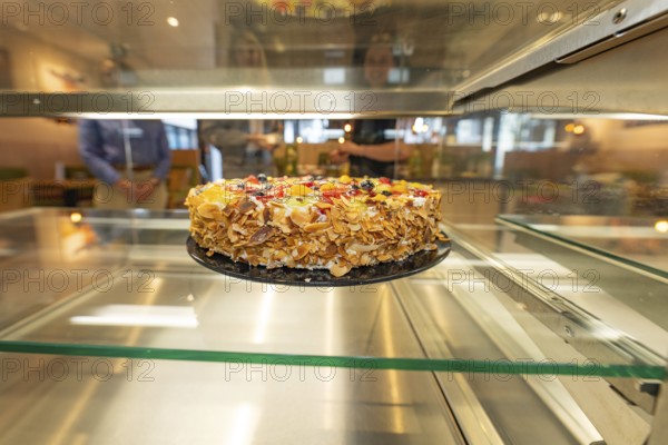 An artistically decorated cake with almond slivers and fruit in a glass display case, Cafe Kuh, Deckenpfronn, Germany, Europe