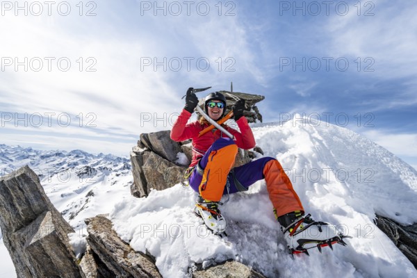 Happy mountaineer with ice axes and crampons on the summit of Piz Grialetsch in winter, Graubünden Haute Route, Albula Alps, Rhaetian Alps, Graubünden, Switzerland, Europe