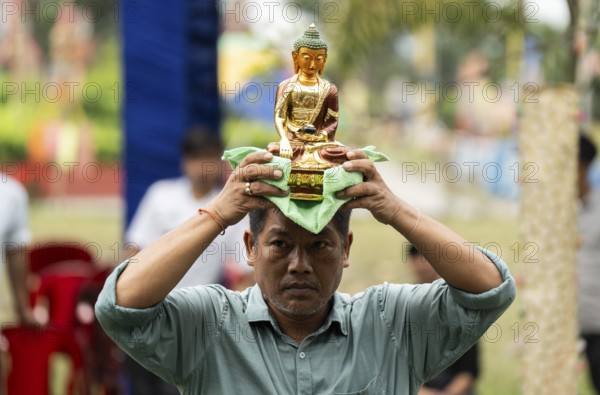 NAMSAI, INDIA.- APRIL 16: A devotees carries the idol of Lord Buddha as he celebrate the vibrant Sangken Festival at Golden Pagoda in Namsai, India on 16 April 2025. Sangken Festival is a beautiful and culturally rich water festival celebrated primarily by the Theravada Buddhist communities, it marks the Buddhist New Year, typically falling in mid-April