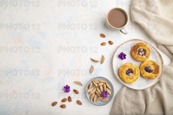 Small cheesecakes with jam and almonds with cup of coffee on a white concrete background and linen textile. top view, flat lay, copy space