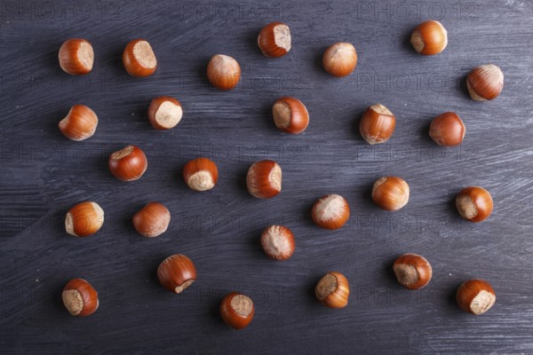 Pattern and texture made from hazelnuts on black wooden background, flat lay. top view