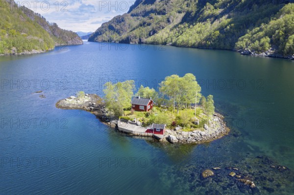 Typical red norwegian cottage on a little island in the fjord, aerial view, Lovrafjord, Norway, Europe