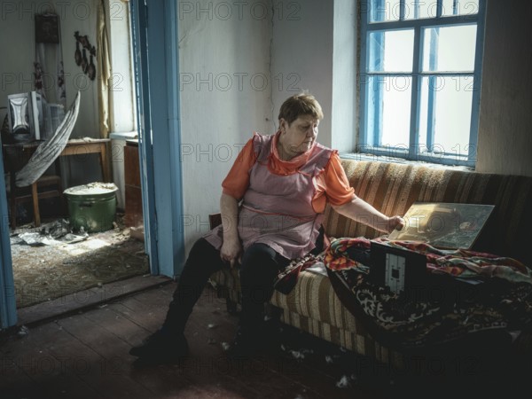 Irina in her small house on the front line, most of it destroyed by shelling, in winter she heats a room with a small stove, Kurahovka, Ukraine, Europe