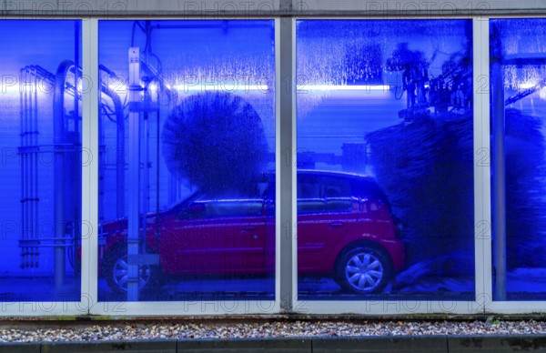 Car in an automatic car wash, car wash tunnel, cleaning foam is sprayed on, rotating brushes clean the vehicle
