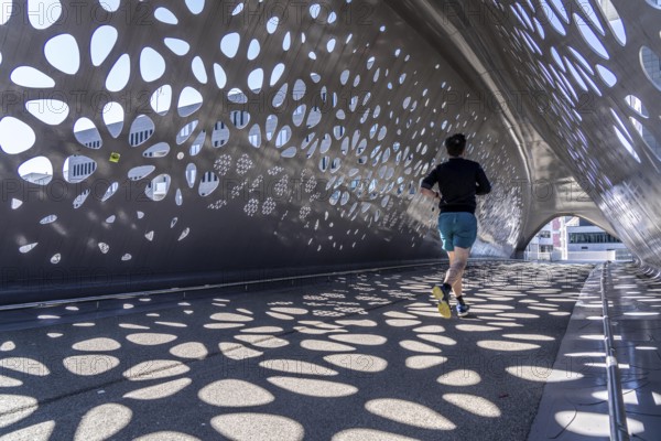 Light effects from the sun in the Parkbruk, a cycle and pedestrian bridge in the city centre of Antwerp, spanning a multi-lane city centre road with tram lines, and thus connecting two lively city districts Kop Spoor Noord and Eilandje, Belgium, without any crossings, Europe