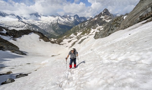 Mountaineer crossing a snowfield, ascent to the Nördliche Mörchnerscharte, mountain peak with snow and glacier in the background, Berliner Höhenweg, Zillertal Alps, Tyrol, Austria, Europe