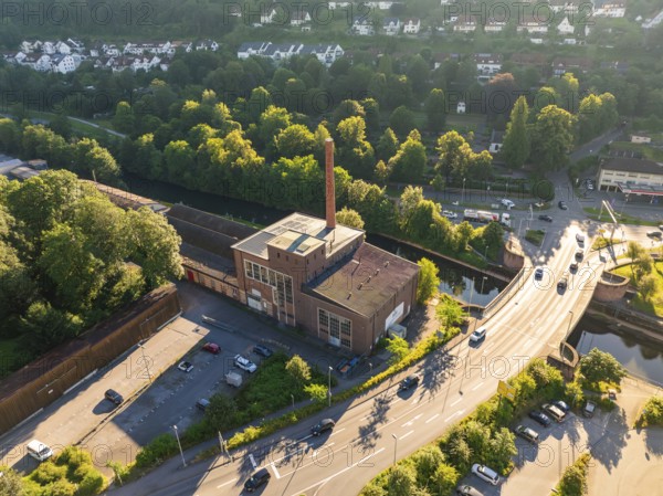 Aerial view of an industrial building on a street in an urban environment with lots of greenery and trees in the evening light, Calw, Black Forest, Germany, Europe