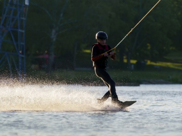 Young man with wakeboard in lake, water sports, water skiing in wakepark