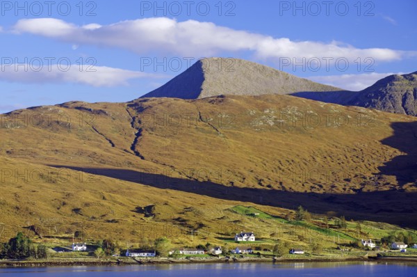 A tranquil inlet lies against a mountainous landscape of isolated houses and a blue sky, Cullins, October, Hebrides, Isle of Skye, Hebrides, Scotland, United Kingdom, Europe