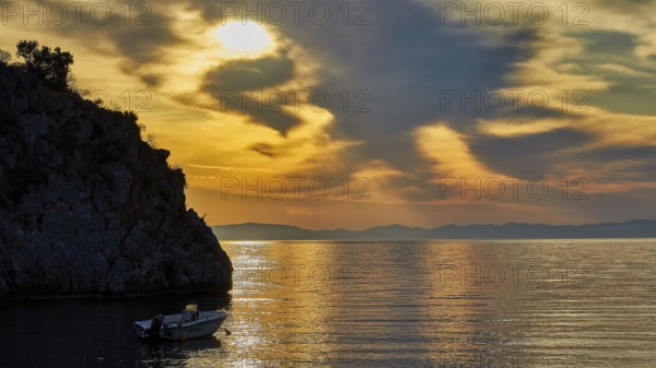 Atmospheric sunrise over the sea with cliffs and a boat, Mani Peninsula, Peloponnese, Greece, Europe
