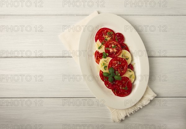 Caprese salad, Italian traditional dish, tomatoes with mozzarella cheese, basil and spices, top view, no people