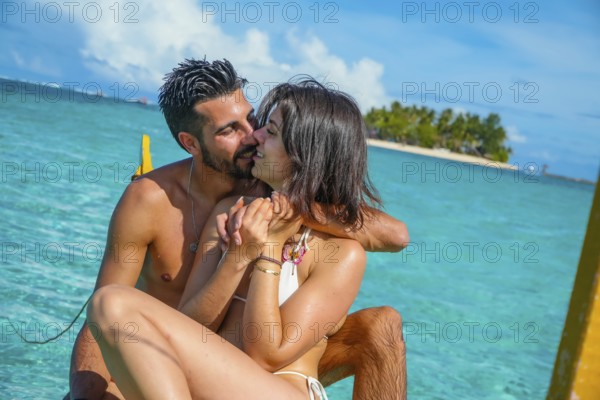 Romantic couple enjoying a kiss while relaxing on a traditional banca boat in the clear turquoise waters of siargao island, philippines