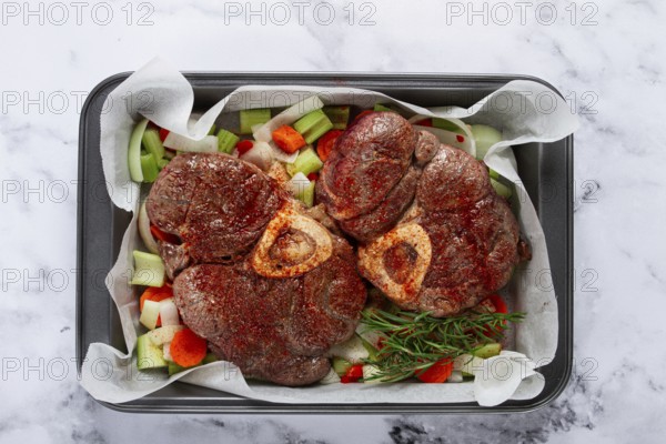 Fried meat on the bone, raw, chopped vegetables, ingredients in the oven, for cooking ossobuco, top view, no people