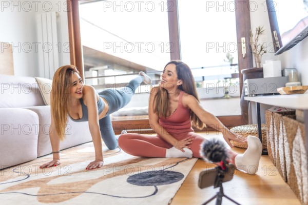 Two fitness trainers recording online yoga class at home using smartphone and microphone, promoting healthy lifestyle during quarantine