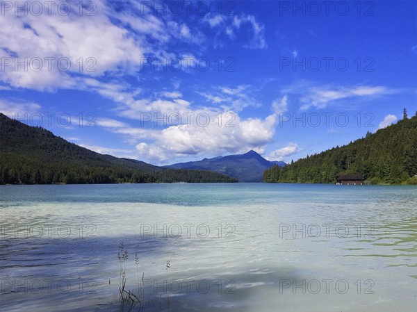 A clear lake with surrounding mountains and wooded slopes under a blue sky with white clouds, Walchensee, Jachenau, Bavaria, Germany, Europe