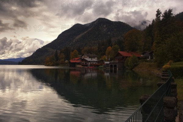 Autumnal lake landscape with houses and mountains in the background under a cloudy sky, Walchensee, Kochel am See, Bavaria, Germany, Europe