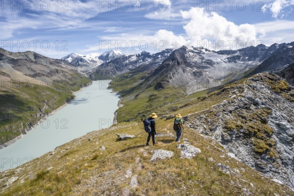 Two mountaineers on the summit of Mont de la Blana, view of a blue mountain lake, Lac des Dix reservoir, mountain peak Mont Blanc de Cheilon with glacier in the background, Hérménence, Valais Alps, Valais, Switzerland, Europe