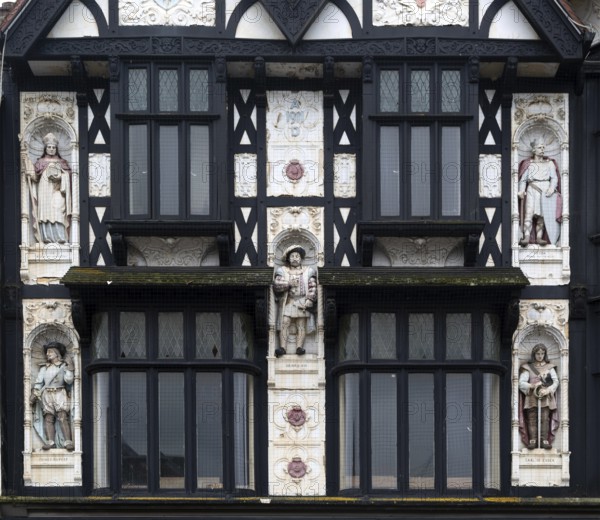 Half-timbered upper elevation painted statues, Peterborough, Cambridgeshire, England, UK designed as a Boots shop architect Michael Vyne Treleaven 1911