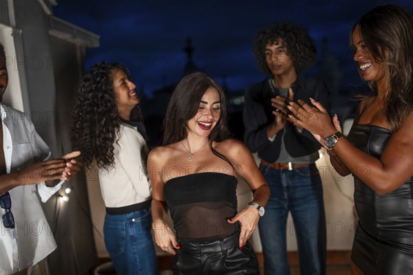 Sensual young woman dancing with friends at night at home in the roof