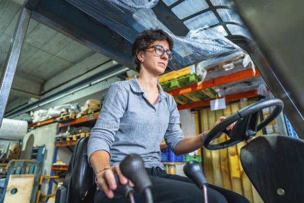 Concentrated cacuasian adult woman working with forklift in a warehouse of a metallurgic factory