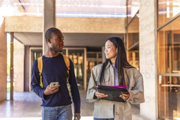 Frontal photo of two multiracial students talking walking along university
