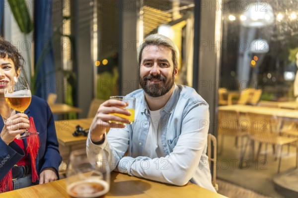 Man drinking cocktail with friends enjoying night life sitting relaxed on a roof terrace of a bar