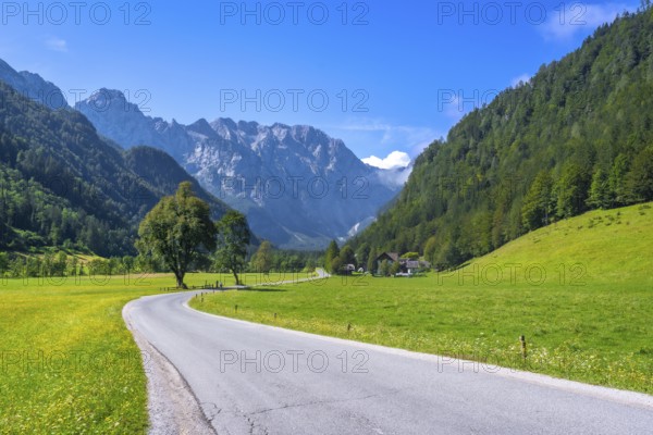 Winding road meandering through the picturesque logarska dolina valley, surrounded by lush meadows and towering mountains in slovenia
