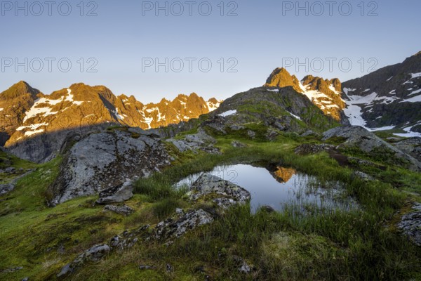 Rocky mountain peaks with reflection, small pond in moor landscape at Trollfjord Hytta, mountain landscape with alpenglow at sunrise, at Trollfjord, Lofoten and Vesterålen, Nordland, Norway, Europe