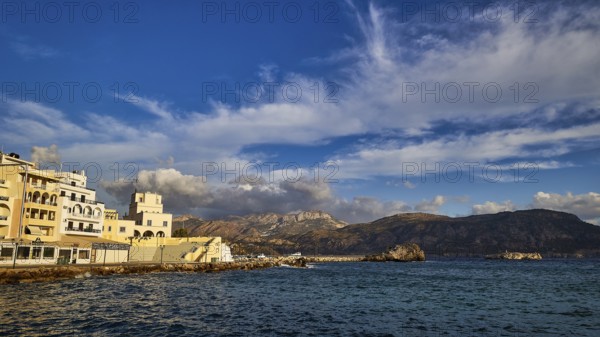 Morning light, coastal town with buildings by the sea and mountains in the background, Pigadia, town and harbour, Pigadia Bay, main town, Karpathos, Dodecanese, Greek Islands, Greece, Europe