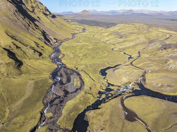 Road F232 Öldufellsleid, ford at waterfall of river bláfjallakvísl, along northern slopes of moss-covered Mt. Öldufell, Mt. Maelifell in the back, black lava sand, aerial view, Iceland, Europe