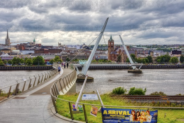 Modern bridge over a river in cloudy weather, in the background a city, Londonderry