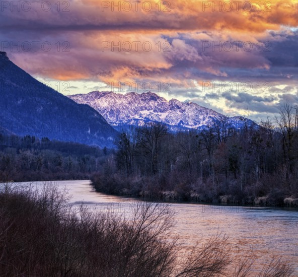Mountain landscape at sunset with river, snow-covered peaks and dramatic cloudy sky, River Inn, near Neubeuern