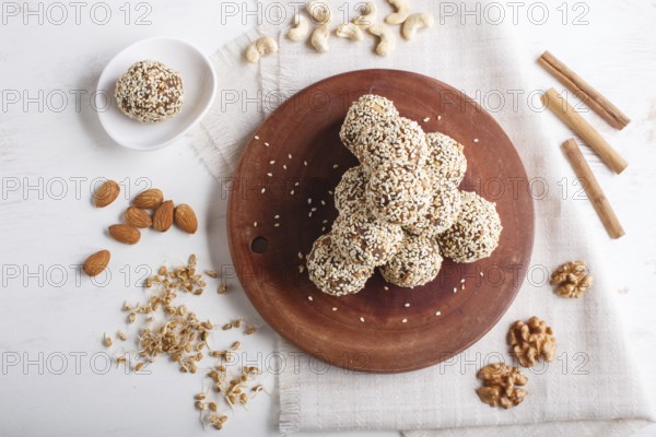 Energy balls cakes with almonds, sesame, cashew, walnuts, dates and germinated wheat on wooden board on white background. top view