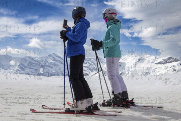 Two skiers in front of the panorama of the Bernese Alps in Grindelwald, Switzerland, Europe