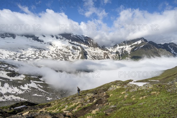 Mountaineer on a hiking trail with high fog in the valley, summit Hochfeiler, Hoher Weißzint and Hochsteller with clouds, glacier Schlegeiskees, Berliner Höhenweg, Zillertal Alps, Tyrol, Austria, Europe