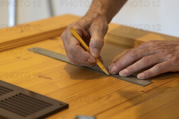 Hands using a ruler and drawing lines on wood in close-up