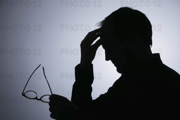 Symbolic photo on the subject of overload. Silhouette of a man rubbing his aching head. Berlin, 22/08/2024