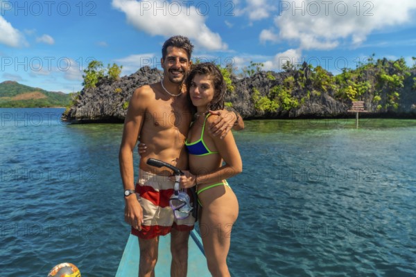 Couple enjoying a snorkeling trip in coron island, philippines, embracing on a traditional bangka boat