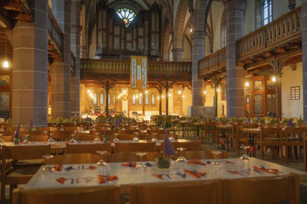 Several laid tables in a warmly lit church with organ in the background, Vesperkirche Calw, Black Forest, Germany, Europe