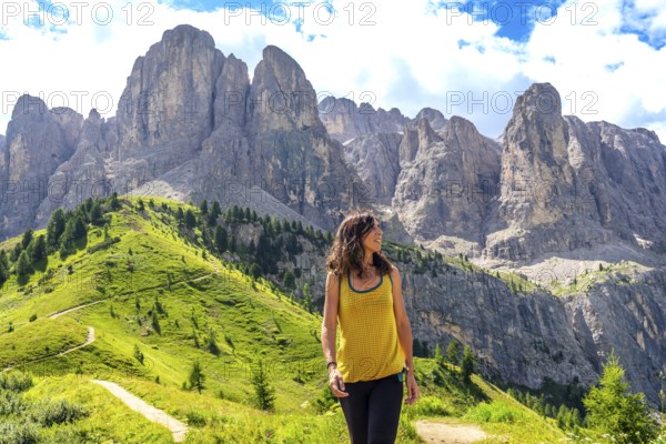 Woman enjoying a sunny summer day while walking through the picturesque dolomites at gardena pass, surrounded by stunning mountain scenery