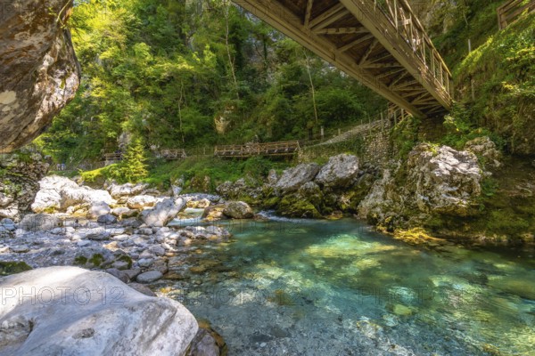 Turquoise water flowing through tolmin gorges under a wooden bridge on a summer day in slovenia