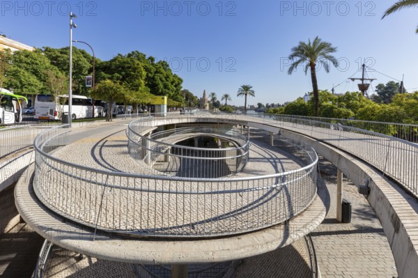 Modern pedestrian bridge with circular paths and palm trees in sunny weather, Seville