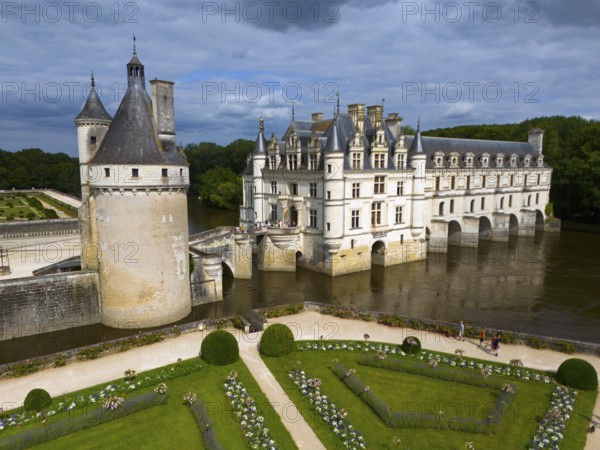 Frontal view of an imposing castle on the river Cher with manicured gardens and dramatic cloudy sky, aerial view, Chenonceau Castle, Château de Chenonceau, moated castle, Chenonceaux, France, Europe