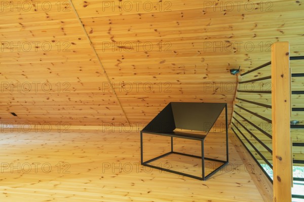 Black metal sitting chair and tubular railings with wooden post in home office set-up on mezzanine inside a piece sur piece Scots pine log home, Quebec, Canada, North America