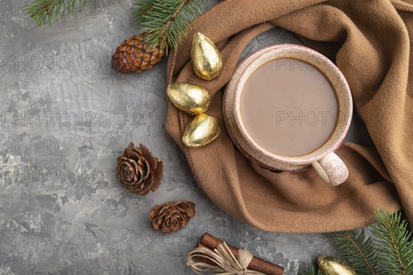 Christmas or New Year composition. Decorations, cones, cinnamon, fir and spruce branches, cup of coffee, wool scarf on a gray concrete background. Top view, close up, flat lay