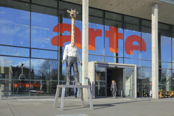 Entrance to the modern building of the ARD and ZDF broadcasting station Arte with sculpture Giraffe Man by Stephan Balkenhol, modern art, giraffe figure, giraffe man, animal figure, man figure, mythical creature, inscription, glass wall, television station, broadcasting, Strasbourg, Bas-Rhin, Alsace, France, Europe