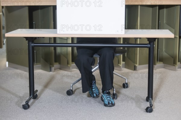 A person sits in a polling booth during voting for the election to the 21st Bundestag at the IHK Potsdam polling station on 23 February 2025