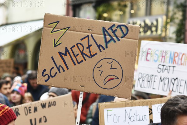 Heidelberg, Germany - February 12th 2025: Person holding up sign about CDU politian Merz and right party AfD in crowd at protest against far-right
