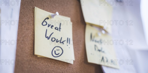 Close up of pinned note ?Great work? on cork board